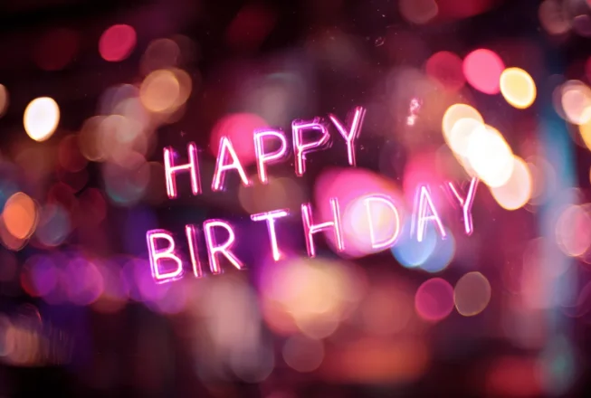 Неоновий напис Happy Birthday на святковому фоні з вогниками
